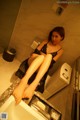 A woman sitting on top of a toilet in a bathroom.