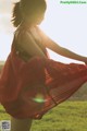 A woman in a red dress standing in a field.