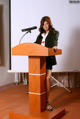 A woman standing at a podium with a microphone.