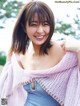 A woman in a blue dress and a pink shawl smiles at the camera.