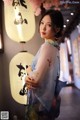 A woman standing in front of a wall with paper lanterns.