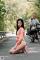 A woman sitting on the side of a road next to a motorcycle.