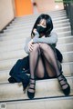 A woman wearing a face mask sitting on a set of stairs.