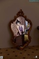 A woman sitting on a bed in front of a mirror.